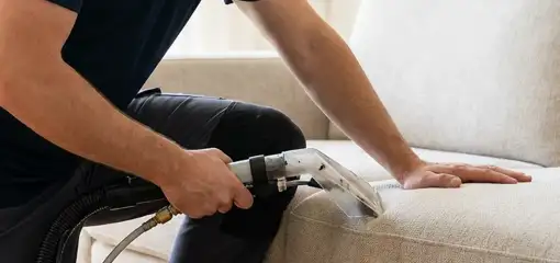 Professional upholstery cleaner deep-cleaning a fabric sofa with a handheld extraction tool, Boulder, CO.